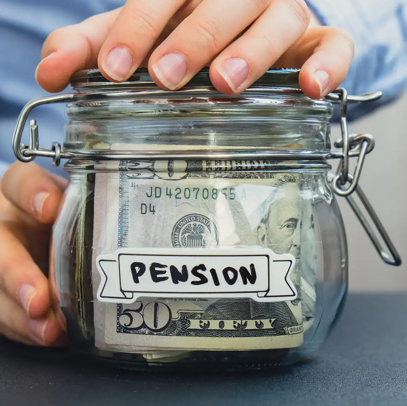Image of a glass jar labeled “PENSION” with folded banknotes inside